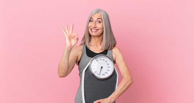 Middle age white hair woman holding a weight scale. fitness and diet concept