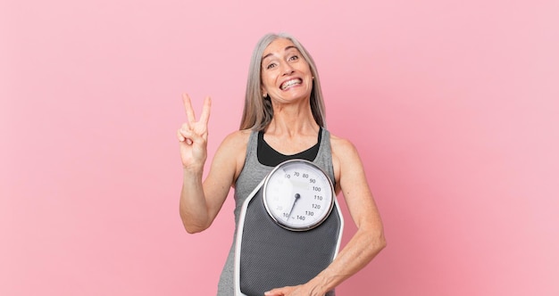 Middle age white hair woman holding a weight scale fitness and diet concept