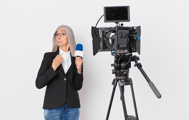 Middle age white hair woman looking arrogant, successful, positive and proud and holding a microphone. television presenter concept