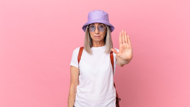 Middle age white hair woman looking serious showing open palm making stop gesture. summer concept