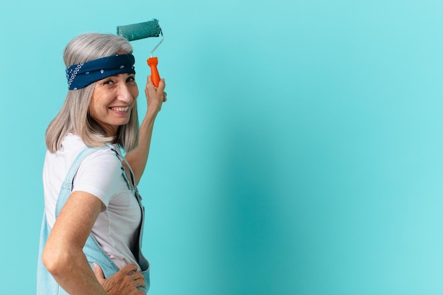 Foto donna di mezza età con i capelli bianchi che dipinge un muro