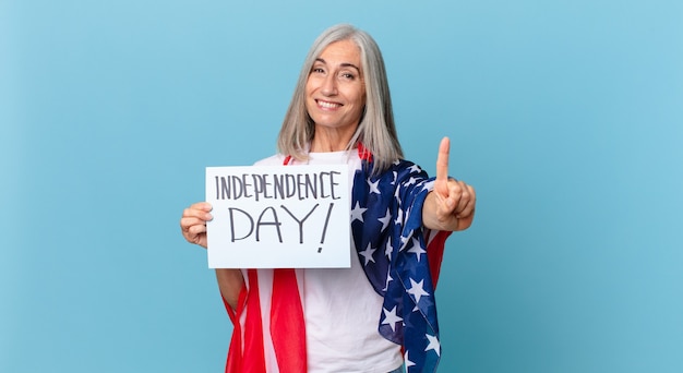 Middle age white hair woman smiling and looking friendly, showing number one. independence day concept