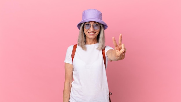 Middle age white hair woman smiling and looking friendly, showing number two. summer concept