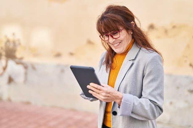 Middle age woman business executive using touchpad at street