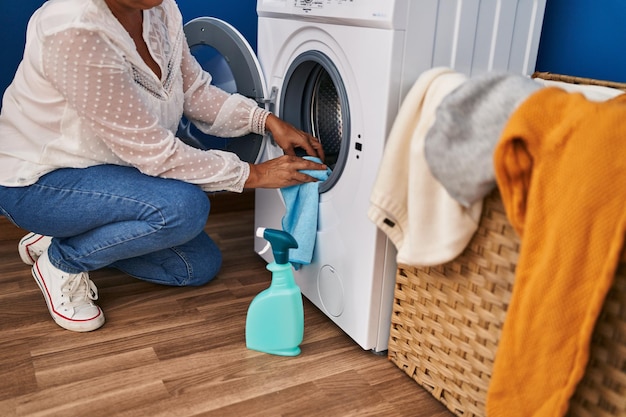 Middle age woman cleaning washing machine at laundry room