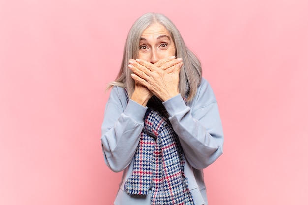 Middle age woman covering mouth with hands with a shocked, surprised expression, keeping a secret or saying oops