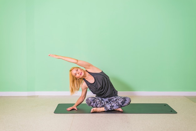 Middle age woman doing yoga on an exercise mat at studio