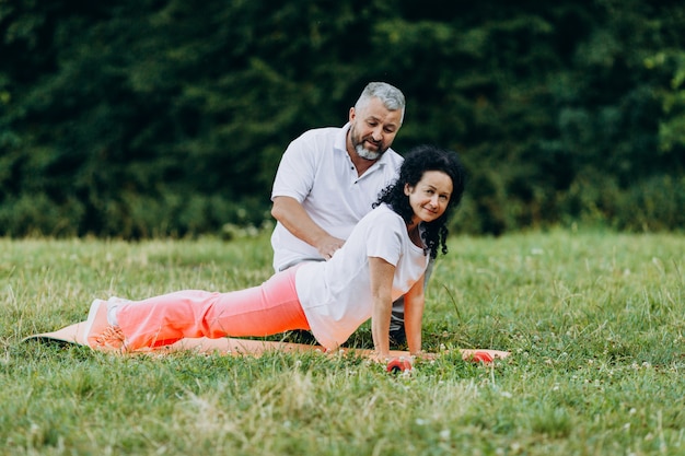 Donna di mezza età che fa yoga. aiuto uomo per donna con esercizio.