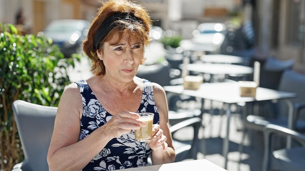 コーヒーショップのテラスでテーブルに座ってコーヒーを飲む中年女性