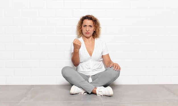 Middle age woman feeling angry, annoyed, rebellious and aggressive, flipping the middle finger, fighting back