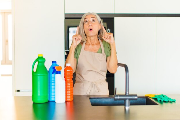 Middle age woman feeling awed and open mouthed pointing upwards with a shocked and surprised look