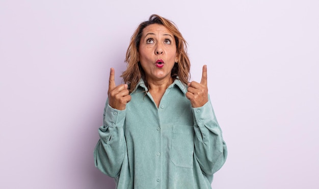 Middle age woman feeling awed and open mouthed pointing upwards with a shocked and surprised look