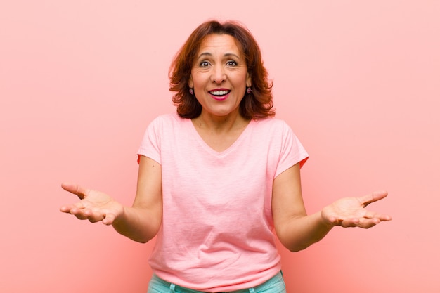 Middle age woman feeling happy, astonished, lucky and surprised