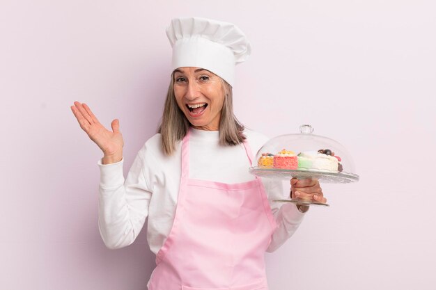 Donna di mezza età che si sente felice e stupita da qualcosa di incredibile concetto di panettiere e torte