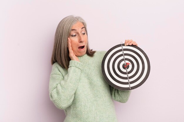 Middle age woman feeling happy excited and surprised darts target concept