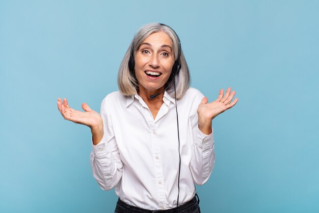 Middle age woman feeling happy, excited, surprised or shocked, smiling and astonished at something unbelievable. telemarketer concept