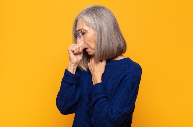 Middle age woman feeling ill with a sore throat and flu symptoms, coughing with mouth covered