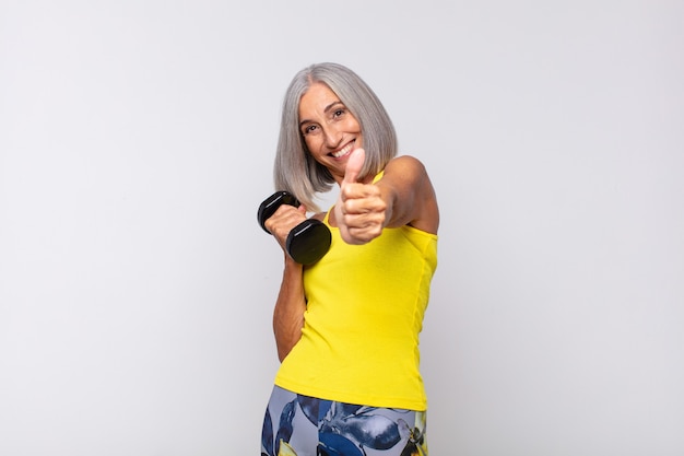 Middle age woman feeling proud, carefree, confident and happy, smiling positively with thumbs up. fitness concept