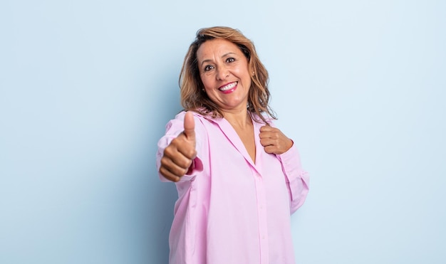 Donna di mezza età che si sente orgogliosa, spensierata, sicura di sé e felice, sorridendo positivamente con il pollice in alto