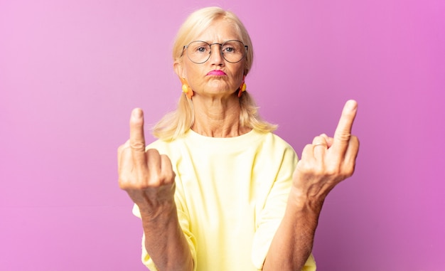 Фото Женщина среднего возраста чувствует себя провокационной, агрессивной и непристойной, щелкая средним пальцем, с бунтарским настроем
