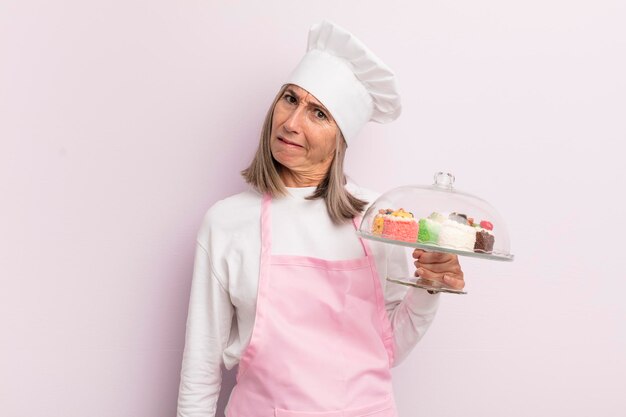 Middle age woman feeling puzzled and confused baker and cakes concept