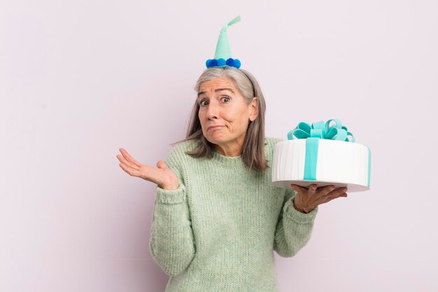 Middle age woman feeling puzzled and confused and doubting bitrthday cake concept