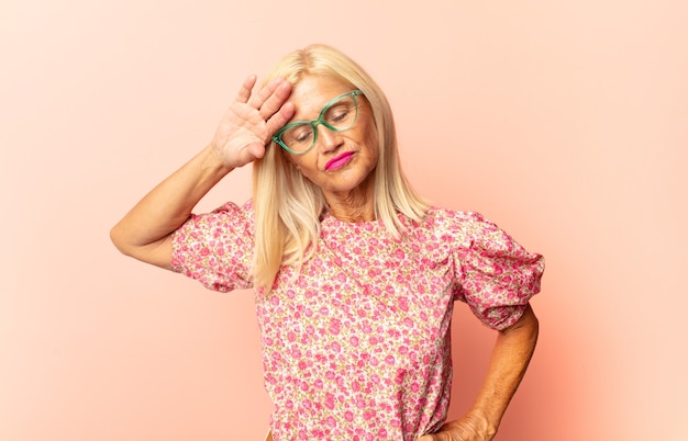 Middle age woman feeling sad, frustrated, nervous and depressed, covering face with both hands, crying