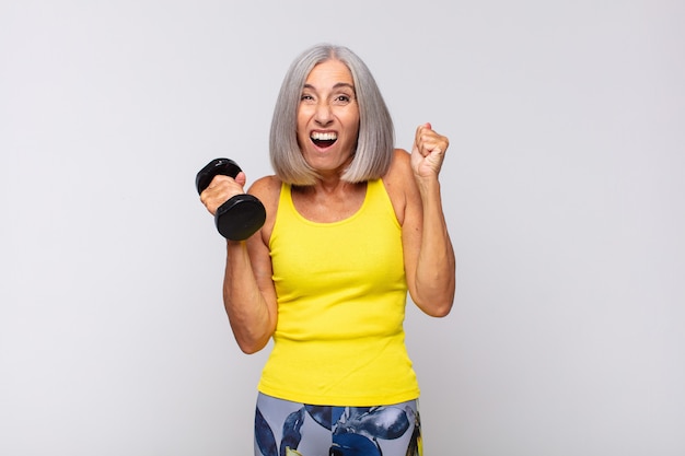 Donna di mezza età che si sente scioccata, eccitata e felice, ridendo e celebrando il successo, dicendo wow !. concetto di fitness