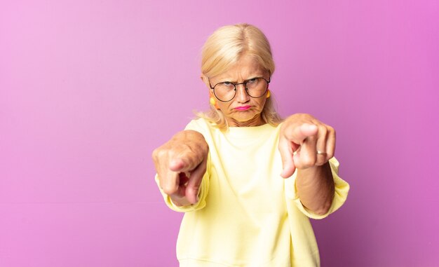 ショックと恐怖を感じ、口を開けて頬に手を当てて恐怖を感じている中年女性