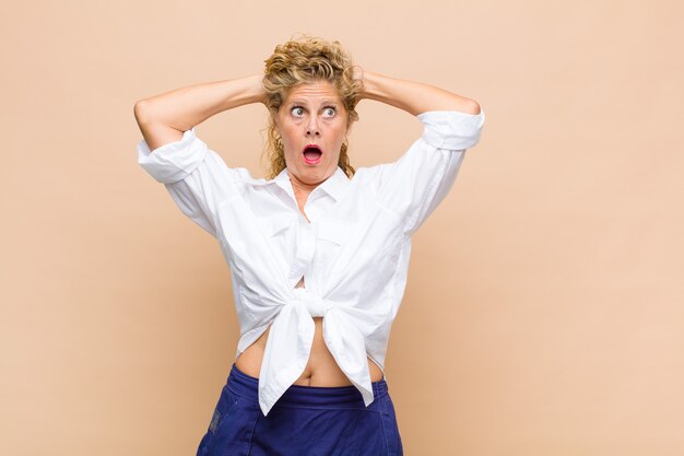 Middle age woman feeling stressed, worried, anxious or scared, with hands on head, panicking at mistake