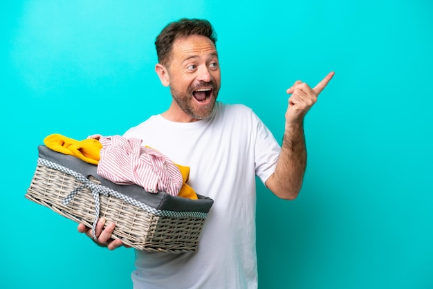 Middle age woman holding a clothes basket isolated on blue background intending to realizes the solution while lifting a finger up