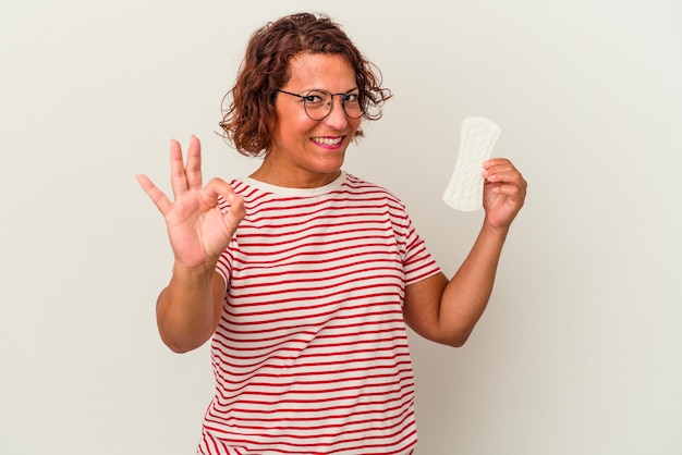 Middle age woman holding a compress isolated on white background cheerful and confident showing ok gesture.