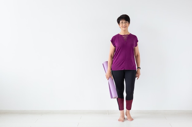 Middle age woman holding mat after a yoga class