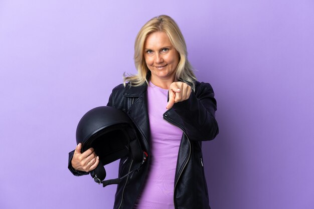 보라색 놀라게 하 고 앞을 가리키는에 고립 된 오토바이 헬멧을 들고 중 년 여자