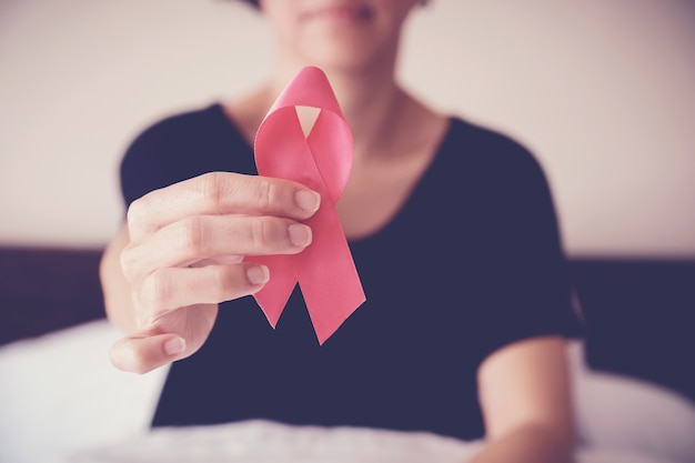 Middle age woman holding pink ribbon, breast cancer awareness