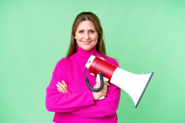 Middle age woman over isolated background holding a megaphone and smiling