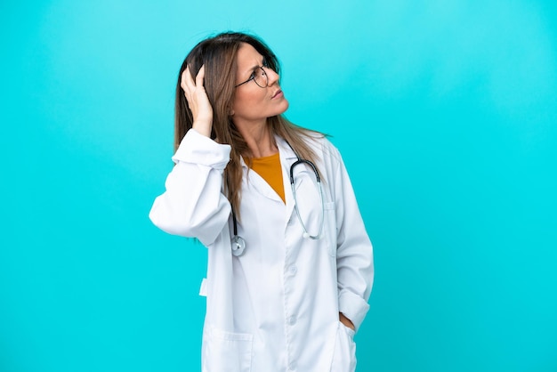 Middle age woman isolated on blue background wearing a doctor gown and having doubts