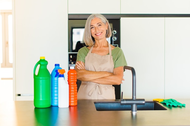 Middle age woman laughing happily with arms crossed, with a relaxed, positive and satisfied pose