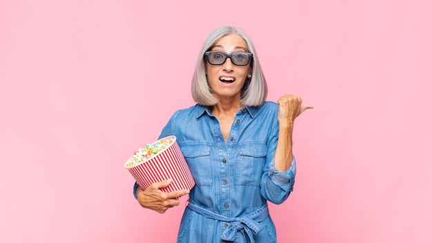 Middle age woman looking astonished in disbelief, pointing at object on the side and saying wow, unbelievable movie concept