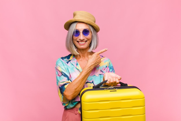 Middle age woman looking excited and surprised pointing to the side and upwards to copy space