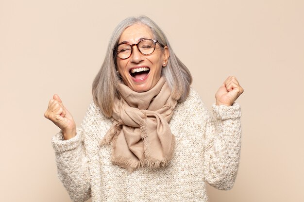 Middle age woman looking extremely happy and surprised, celebrating success, shouting and jumping