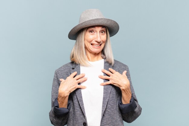 Middle age woman looking happy, surprised, proud and excited, pointing to self