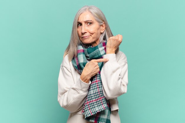 Middle age woman looking impatient and angry, pointing at watch, asking for punctuality, wants to be on time