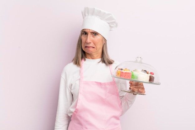 Женщина средних лет выглядит озадаченной и смущенной концепцией пекаря и тортов