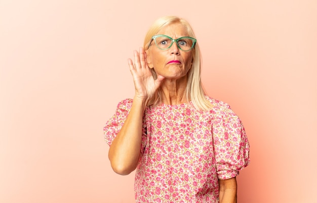 Middle age woman looking serious and curious, listening, trying to hear a secret conversation or gossip, eavesdropping