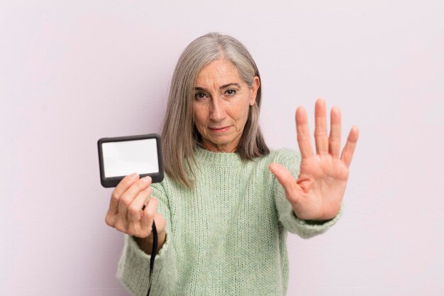 Middle age woman looking serious showing open palm making stop gesture vip pass concept