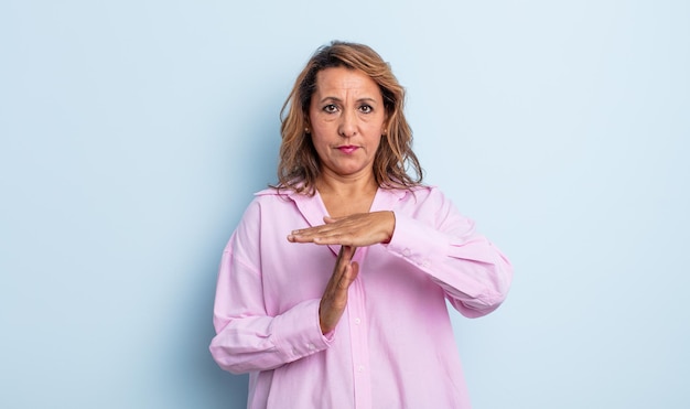 Middle age woman looking serious, stern, angry and displeased, making time out sign