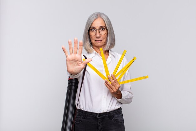 Middle age woman looking serious, stern, displeased and angry showing open palm making stop gesture