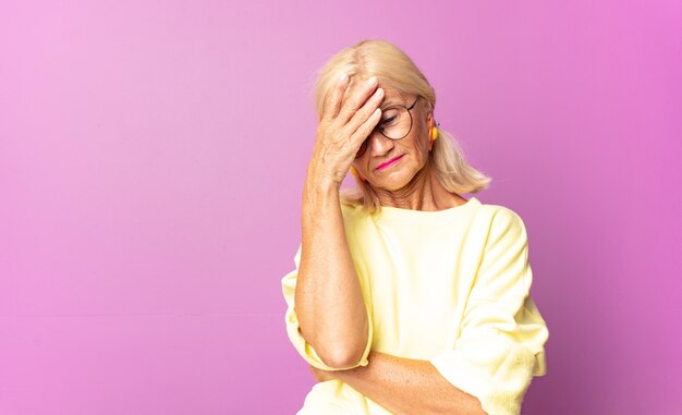 Middle age woman looking stressed, ashamed or upset, with a headache, covering face with hand