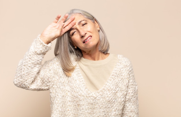 Middle age woman looking stressed, tired and frustrated, drying sweat off forehead, feeling hopeless and exhausted